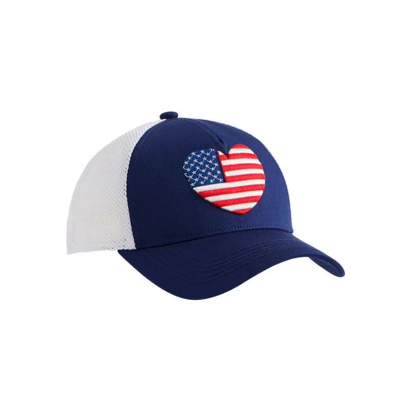 Commercial product photograph of a navy blue and white trucker hat on a plain white background featuring an embroidered heart-shaped American flag with breathable white mesh panels and red and white stripes