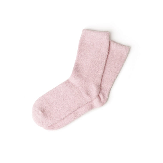 Studio product photograph of a pair of plush pink fuzzy socks set against a minimalist white background featuring a thick microfiber texture and a soft pastel hue arranged in a casual overlap