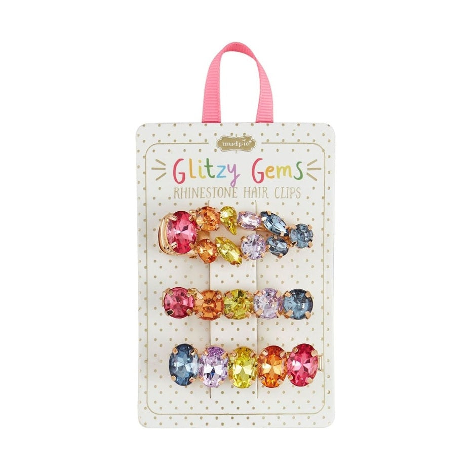 Mud Pie Glitzy Gems rhinestone hair clips featuring three rows of faceted rainbow jewels in marquise and round shapes on a cream polka-dot display card with a pink ribbon loop