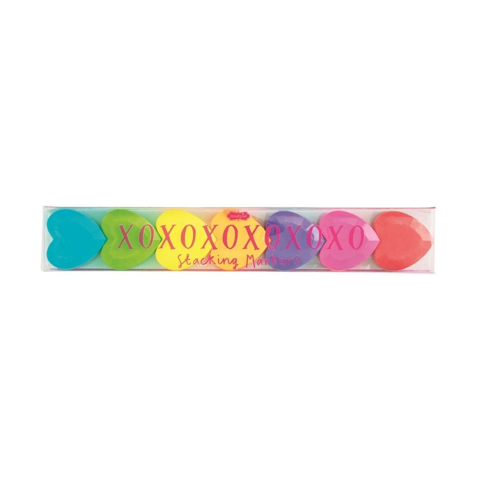 Plastic stacking markers by Mud Pie featuring a sequence of vibrant heart-shaped highlighters in a rainbow spectrum housed within clear packaging with pink XOXO branding against a white background