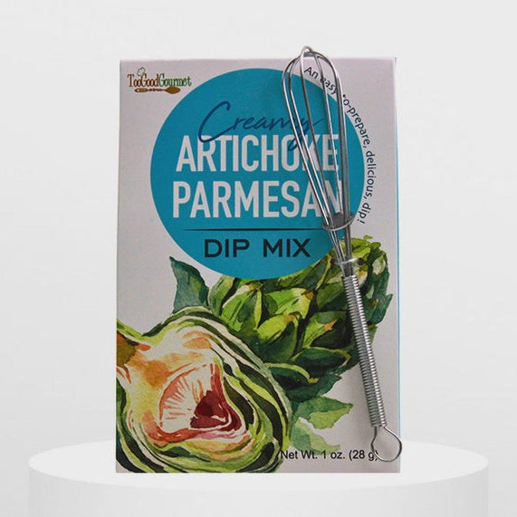 Product photograph of a Too Good Gourmet Creamy Artichoke Parmesan Dip Mix box on a white pedestal featuring a prominent teal circular logo, a vibrant watercolor artichoke illustration, and a small silver wire whisk