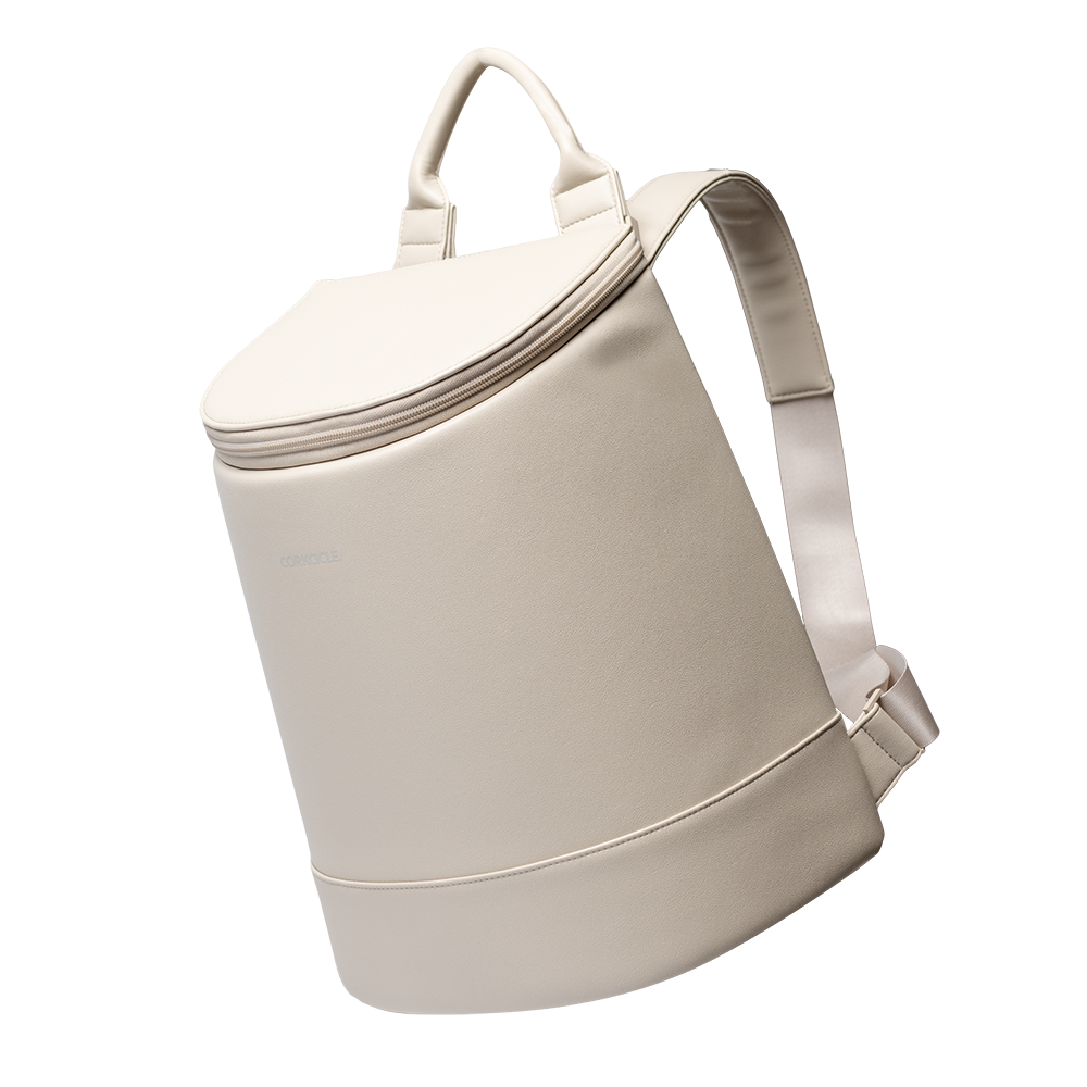 Studio photograph by Corkcicle of a cream-colored Eola Bucket Cooler in a minimalist studio featuring a matte vegan leather finish, a reinforced top handle, and adjustable padded shoulder straps