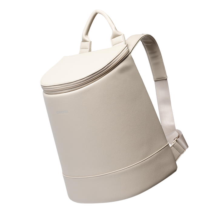 Studio photograph by Corkcicle of a cream-colored Eola Bucket Cooler in a minimalist studio featuring a matte vegan leather finish, a reinforced top handle, and adjustable padded shoulder straps
