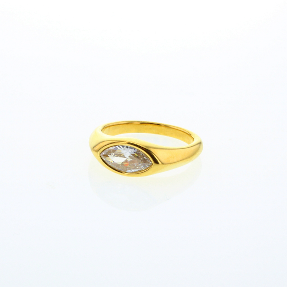 Gold jewelry featuring a marquise-cut clear gemstone in a flush-set yellow gold band on a minimalist white background with a polished finish and soft reflection