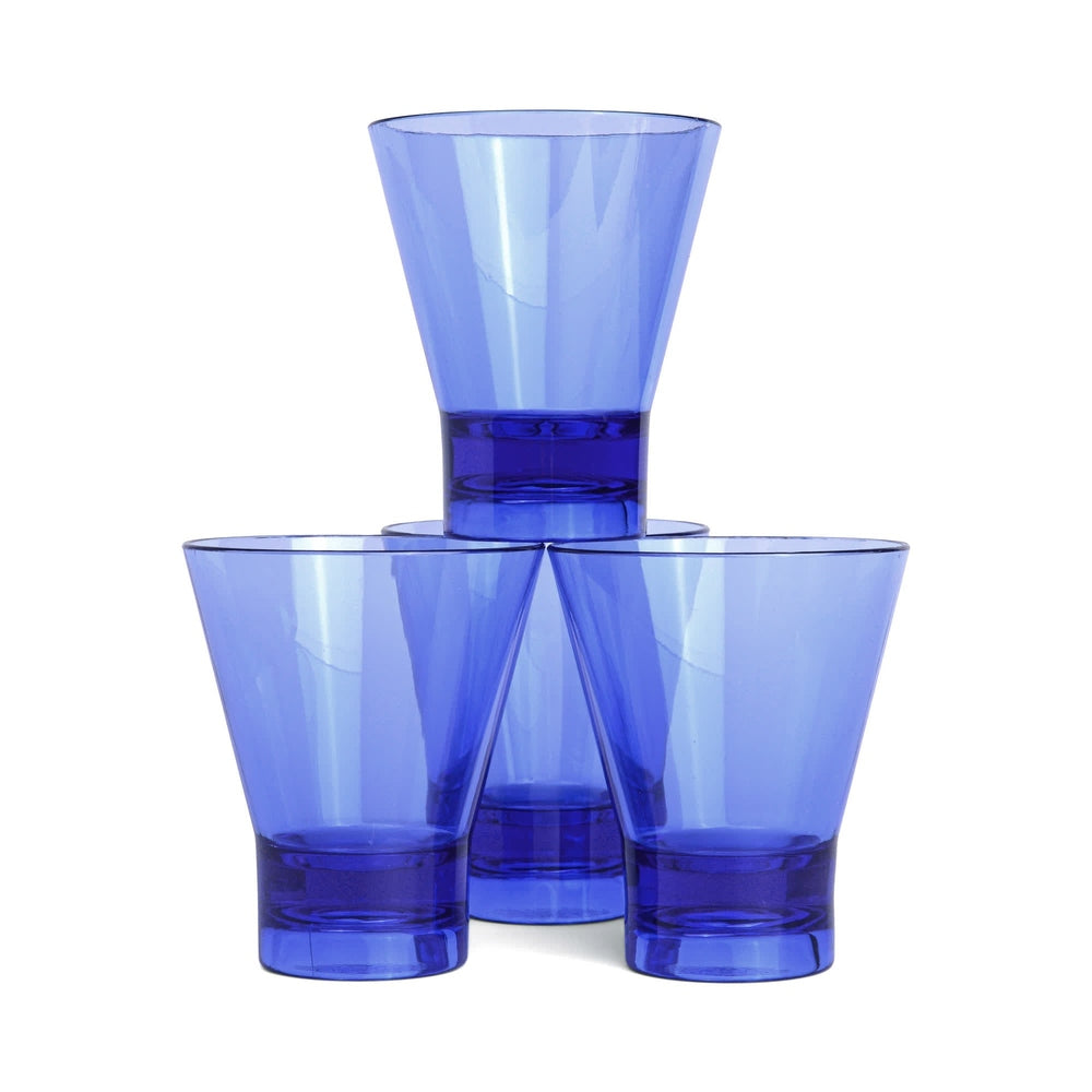 Cobalt blue hand-blown glass by Kosta Boda featuring four tapered tumblers stacked in a pyramid on a neutral white background with thick weighted bases and vibrant translucent rims