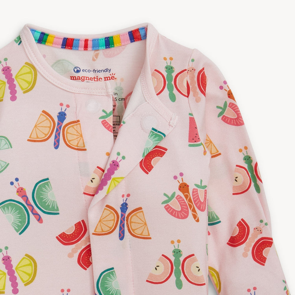 Illustrated fabric print by Magnetic Me on a soft pink baby romper featuring whimsical butterflies with orange and kiwi slice wings, a hidden magnetic closure, and a colorful rainbow-striped collar trim