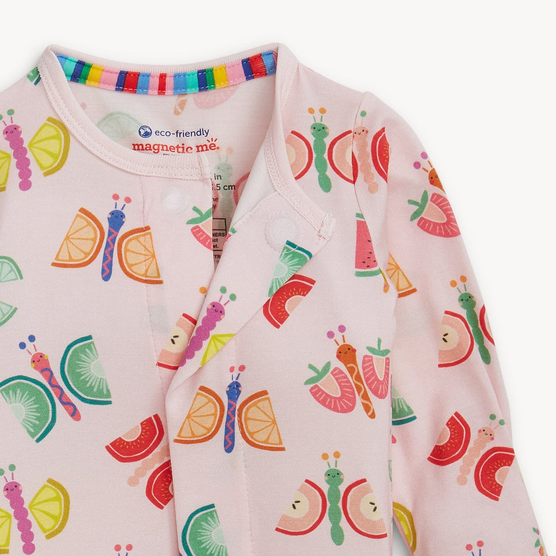 Illustrated fabric print by Magnetic Me on a soft pink baby romper featuring whimsical butterflies with orange and kiwi slice wings, a hidden magnetic closure, and a colorful rainbow-striped collar trim