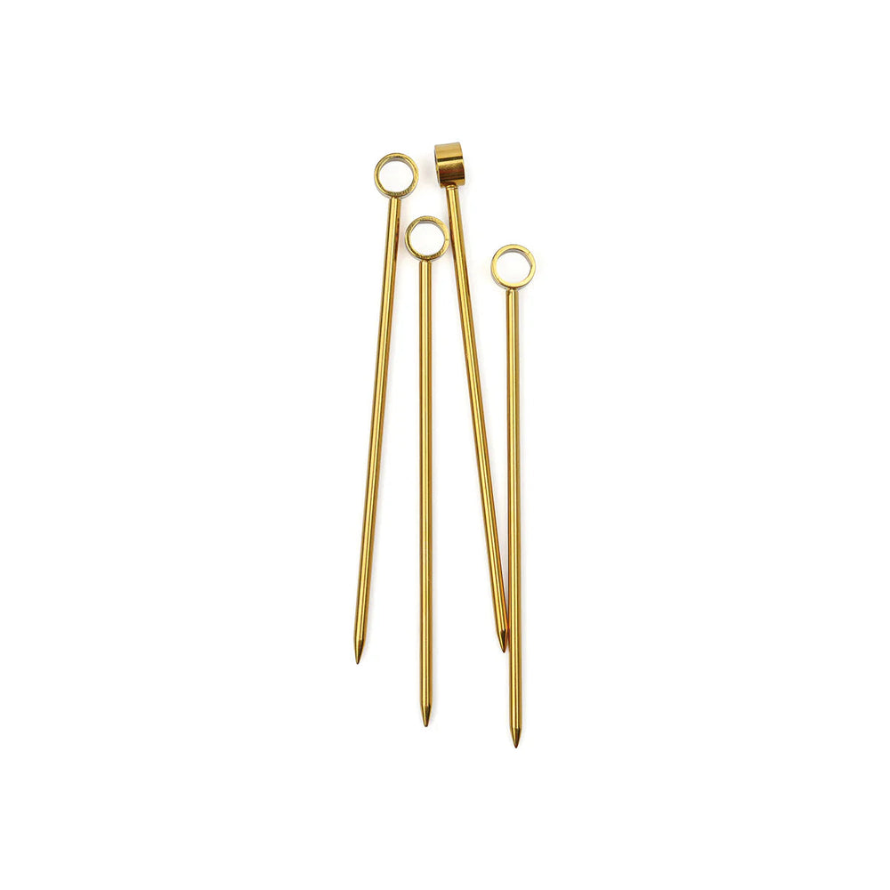 Gold-plated stainless steel cocktail picks displayed on a neutral white background featuring circular ring tops and tapered pointed tips with a polished metallic finish