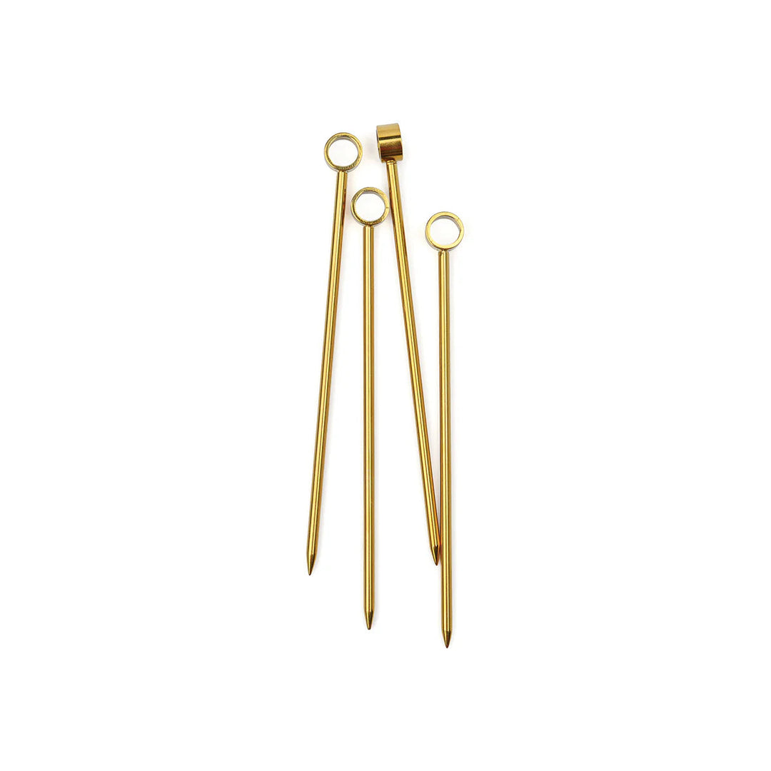 Gold-plated stainless steel cocktail picks displayed on a neutral white background featuring circular ring tops and tapered pointed tips with a polished metallic finish