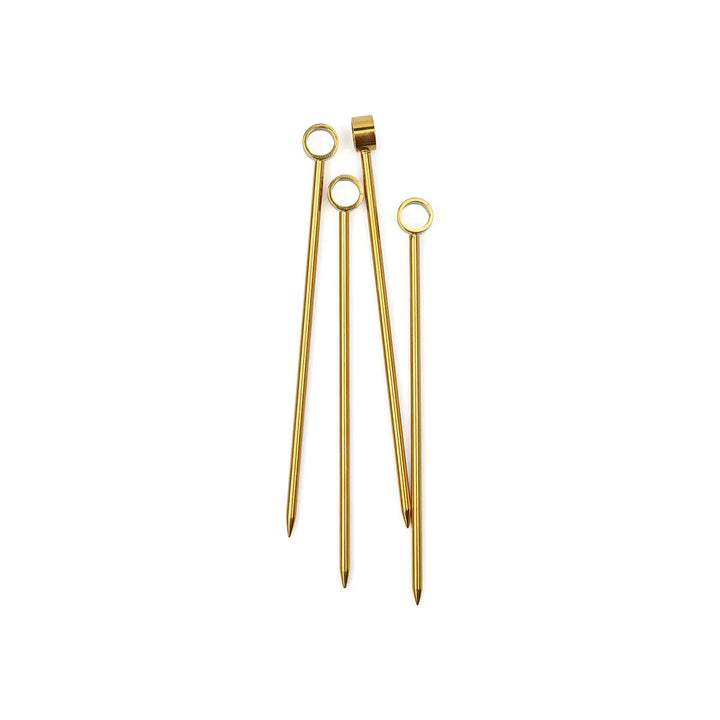 Gold-plated stainless steel cocktail picks displayed on a neutral white background featuring circular ring tops and tapered pointed tips with a polished metallic finish