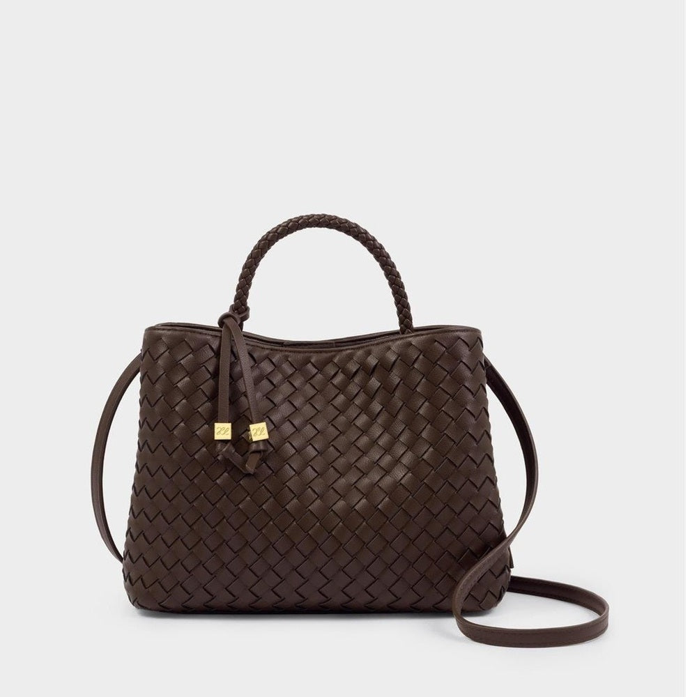 Leather handbag by Loro Piana featuring a dark brown woven leather body, a single braided top handle, and two small gold-tone logo charms against a plain white studio background