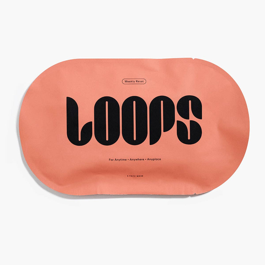 Commercial product photograph for LOOPS Beauty of a single matte peach-colored Weekly Reset face mask packet on a white background featuring bold black stylized typography and minimalist text detailing