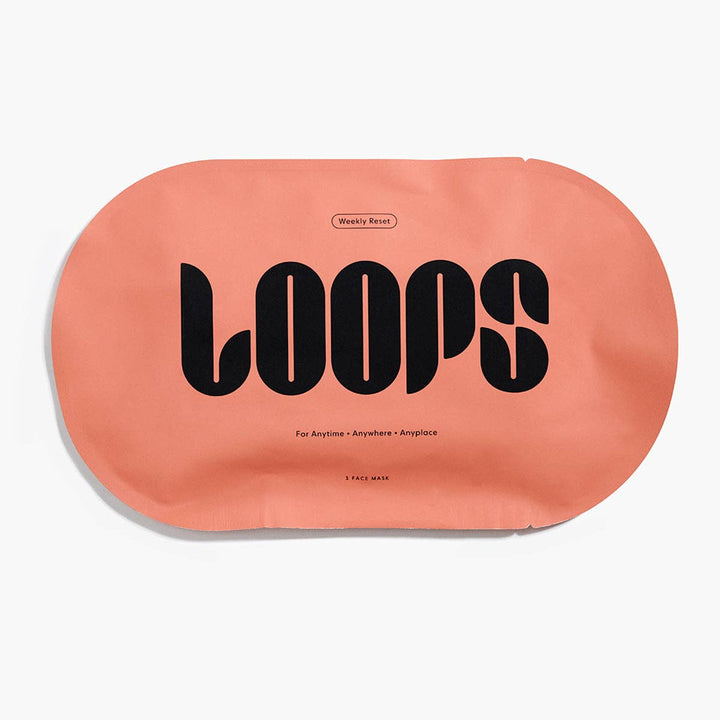 Commercial product photograph for LOOPS Beauty of a single matte peach-colored Weekly Reset face mask packet on a white background featuring bold black stylized typography and minimalist text detailing