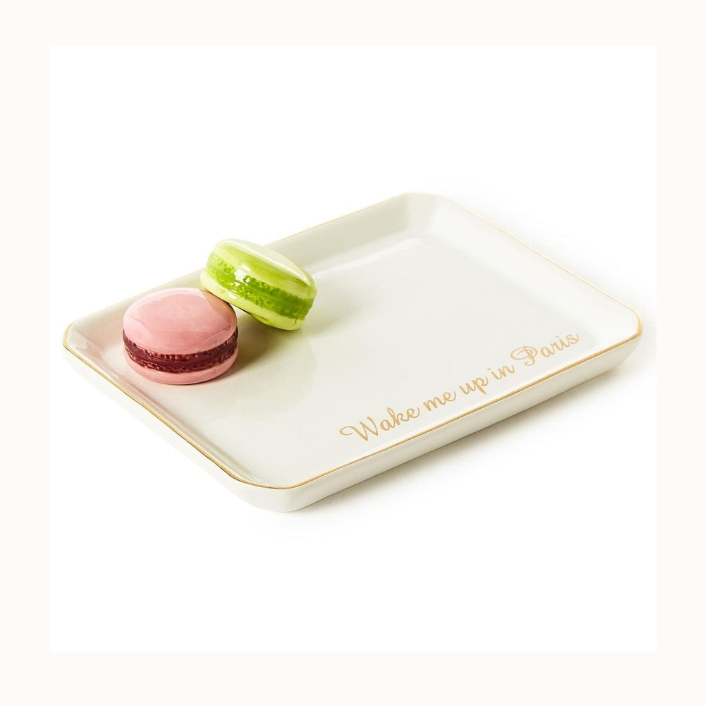 White ceramic trinket tray featuring a pink and lime green macaron beside gold cursive script reading Wake me up in Paris with delicate gold-rimmed edges
