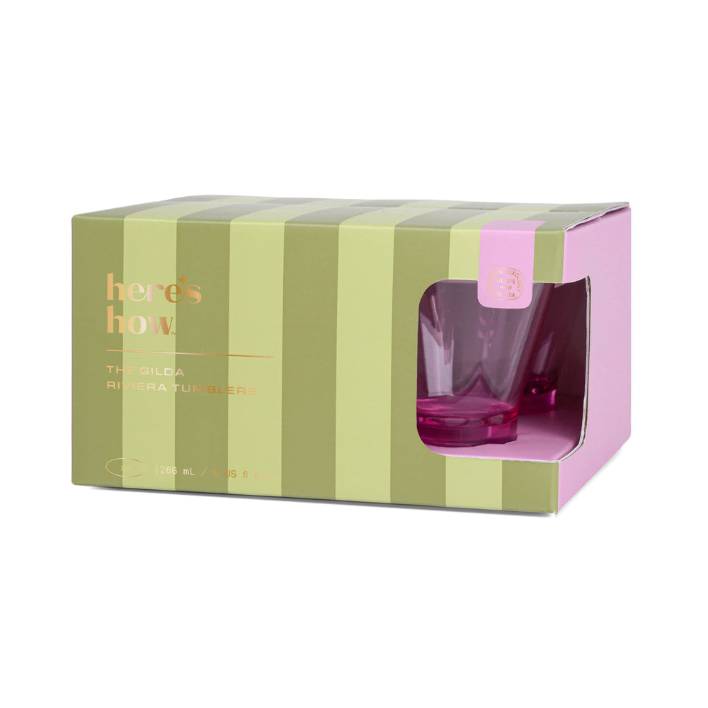Product packaging by Here's How for Gilda Riviera Tumblers featuring olive and lime green vertical stripes, a cutout window revealing vibrant pink faceted glassware, and elegant gold foil lettering on a white background