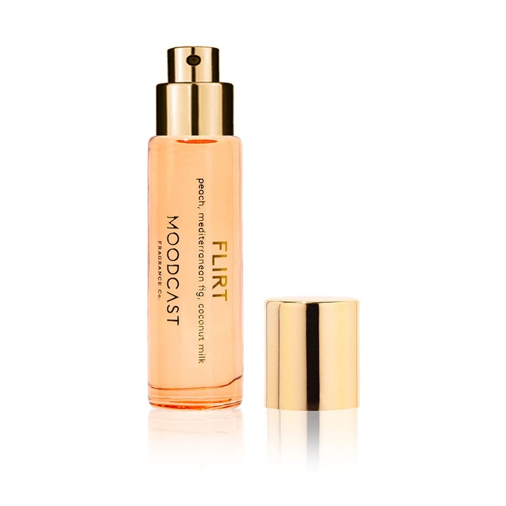 Commercial product photograph by Moodcast Fragrance Co of the Flirt perfume bottle featuring peach-tinted liquid, a reflective gold spray nozzle, and a matching gold cap on a white studio background