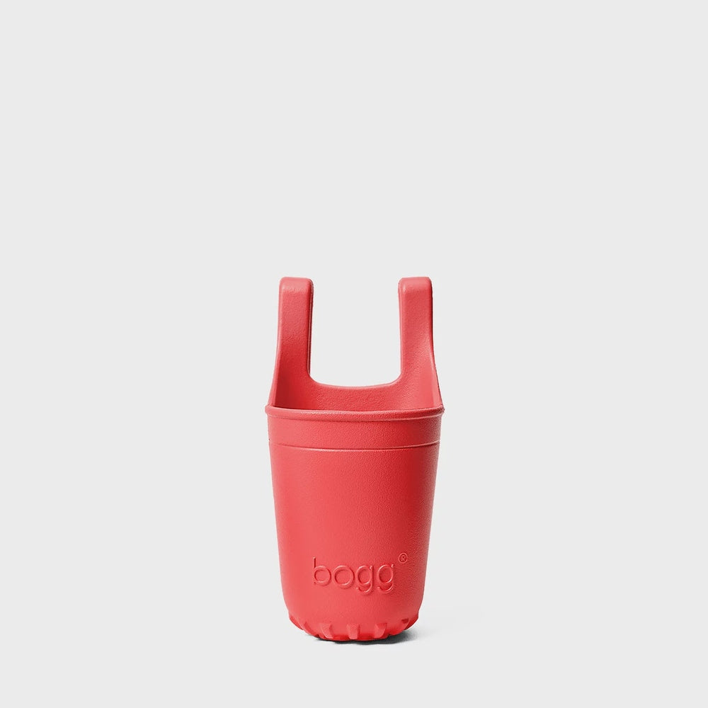 Molded EVA foam by Bogg Bag featuring a vibrant red beverage holder attachment centered on a minimalist gray background displaying the embossed bogg logo and two top hooks with a textured scalloped base