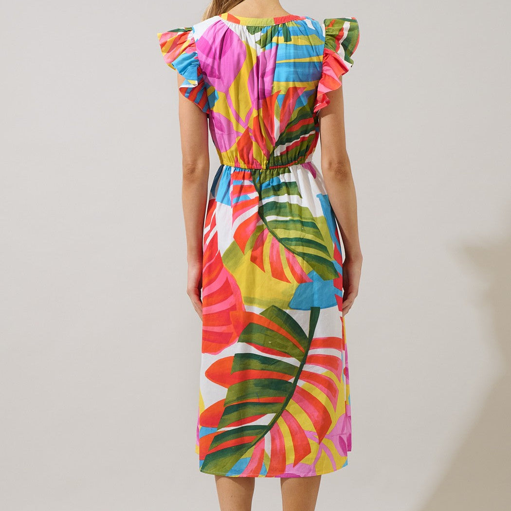 Photograph of a colorful tropical midi dress on a model in a studio featuring large monstera leaf prints, ruffled cap sleeves, and a vibrant palette of pink, yellow, and green