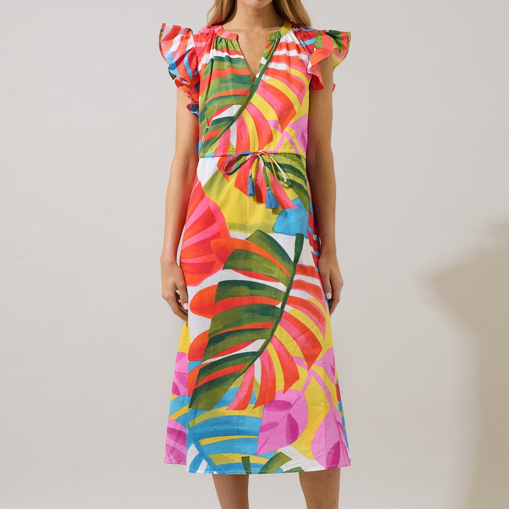 Studio photograph of a woman wearing a vibrant tropical leaf print midi dress featuring flutter sleeves and a blue tassel drawstring waist in a minimalist studio setting