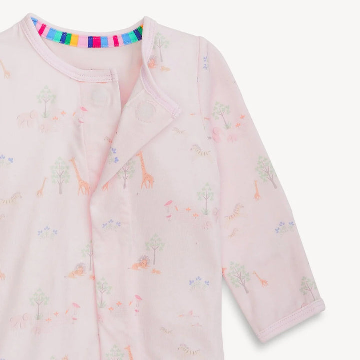 Cotton textile baby sleepsuit displaying a light pink safari savanna print on a white background, showcasing a vibrant rainbow-striped inner neckline, delicate pastel giraffes and lions, and a front snap-button closure