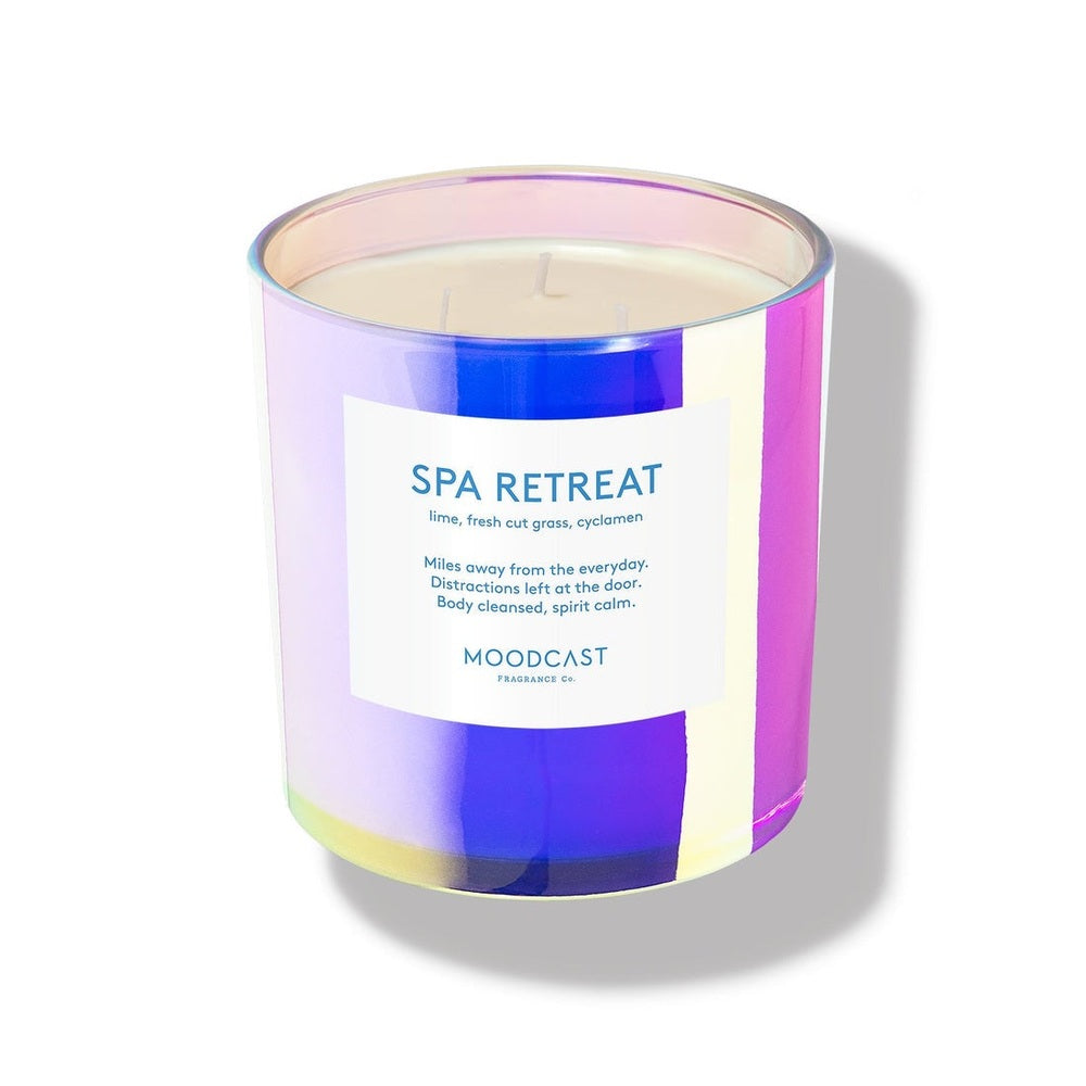 Product photograph of a Moodcast Fragrance Co. Spa Retreat scented candle featuring an iridescent holographic glass jar with purple and blue reflections, cream-colored three-wick wax, and a minimalist white label with blue typography