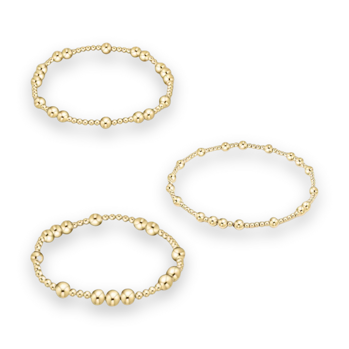 Gold jewelry photography of three beaded stretch bracelets on a white background featuring graduated spherical beads with a high-polish metallic finish and varying ball diameters