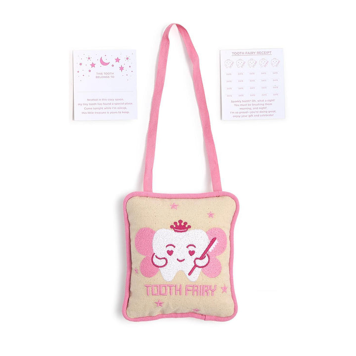 Commercial product photography of a beige canvas tooth fairy pillow kit on a white background featuring a pink embroidered winged tooth wearing a crown alongside paper cards decorated with pink stars and moons