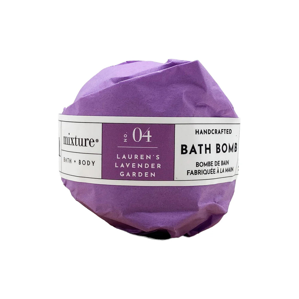 Product photograph by Mixture featuring a handcrafted bath bomb wrapped in crinkled purple paper on a white background, highlighted by a label for No. 04 Lauren's Lavender Garden with black serif text and bilingual French descriptions