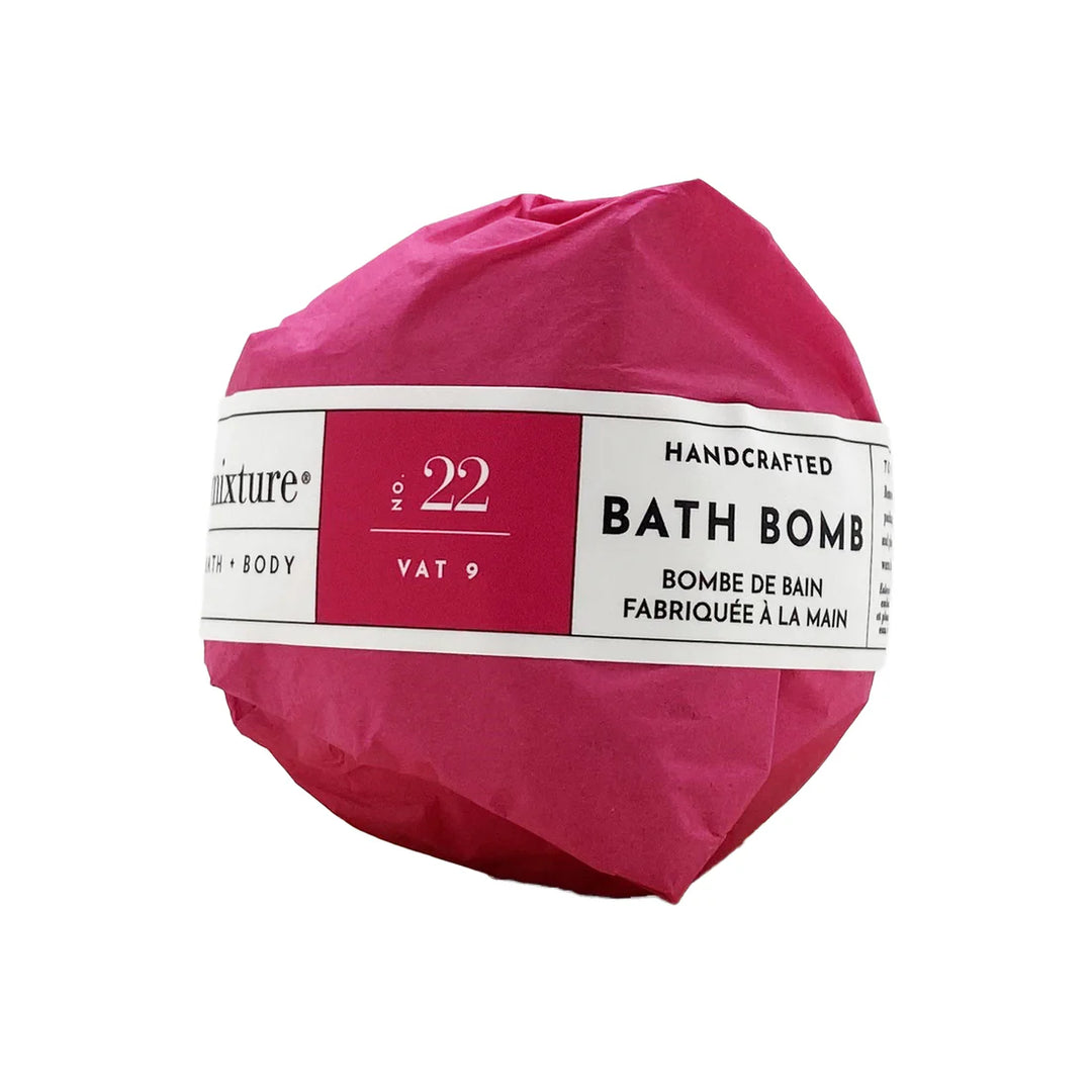 Studio product photograph by Mixture of a handcrafted bath bomb wrapped in vibrant magenta tissue paper featuring a white label with No. 22 and Vat 9 text against a plain white background