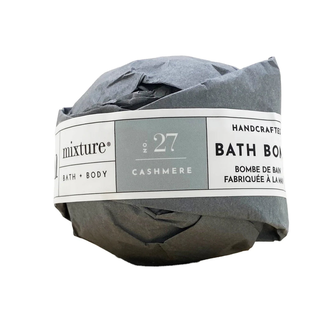 Product photography of a Mixture brand handcrafted bath bomb wrapped in crumpled dark grey tissue paper featuring a clean white and grey label with No. 27 Cashmere text against a plain white background