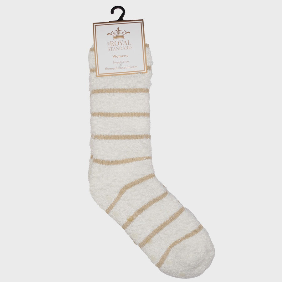 Product photograph by The Royal Standard of a white fuzzy snuggle sock on a neutral background featuring tan horizontal stripes, a plush shaggy texture, and a branded tag with a gold crown logo