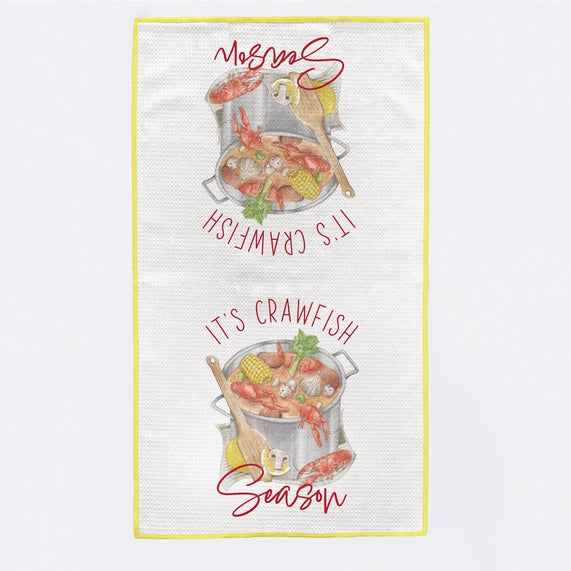 Graphic illustration on a white waffle-weave kitchen towel featuring two mirrored stockpots filled with vibrant red crawfish and yellow corn on the cob framed by the red text IT&