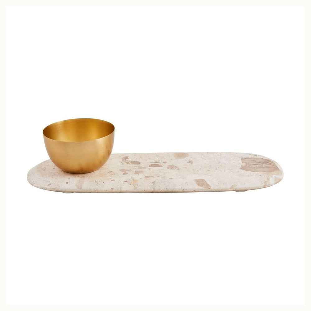 Marble and metal decorative accessory by Tom Dixon featuring a brushed brass bowl on an elongated oval beige stone tray with unique cream and tan speckled inclusions on a white background