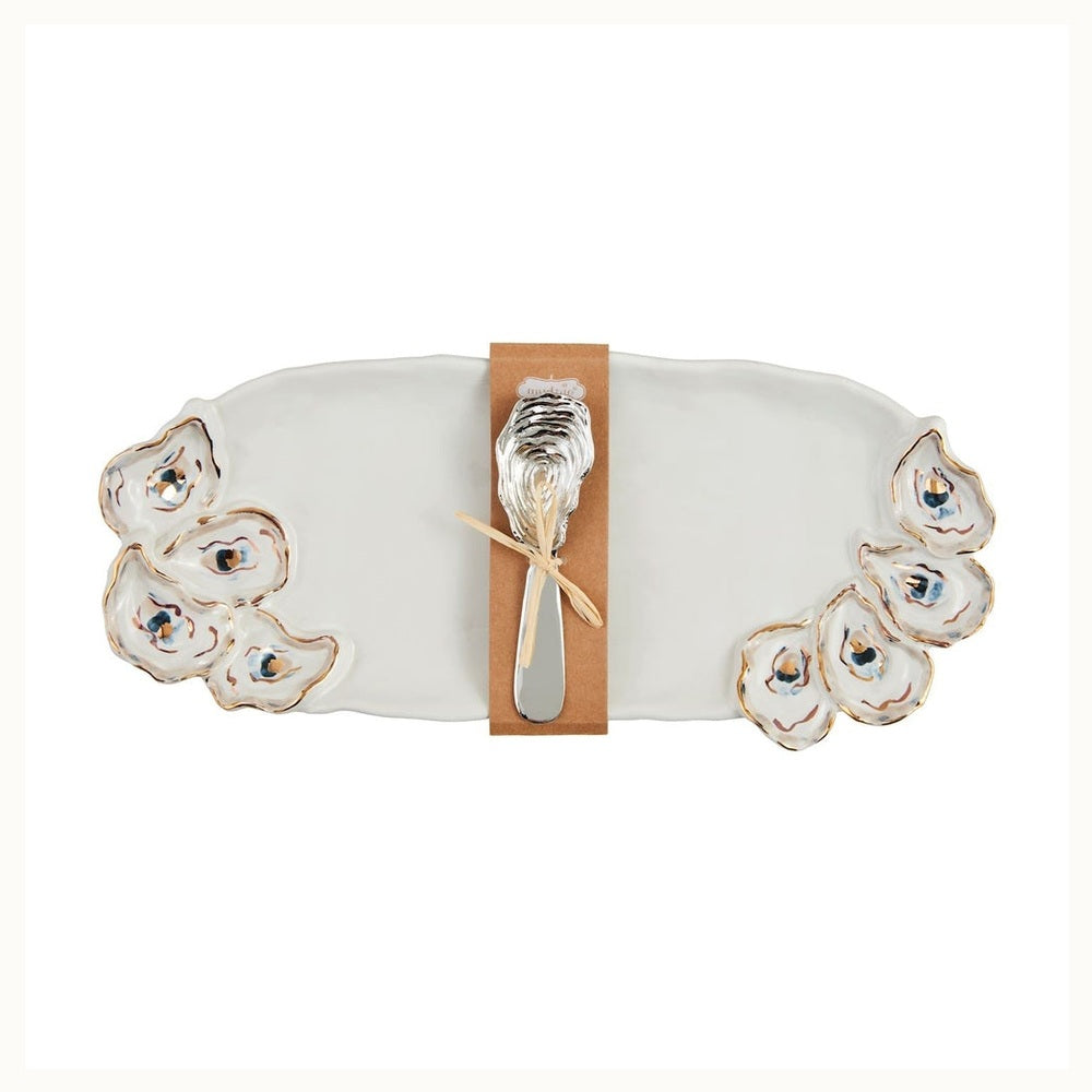 Ceramic stoneware platter by Mud Pie features a white oyster-themed serving tray with gold-rimmed hand-painted shell accents and a silver metal spreader with a textured shell handle secured by a kraft paper band and twine