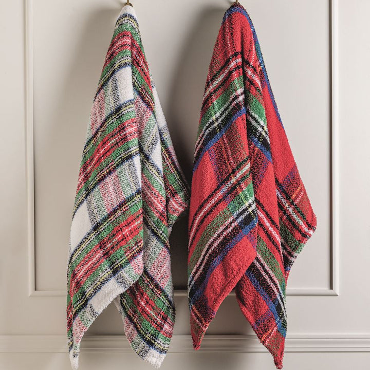 Woven textile hand towels featuring festive red and white plaid patterns hanging on a neutral paneled wall with vibrant green accents and a soft nubby texture