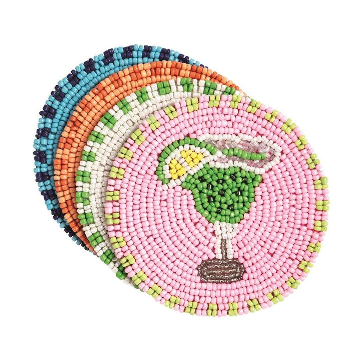 Hand-beaded coasters by an unknown artist featuring a green margarita cocktail icon with a yellow lime wedge on a pink background, layered over blue and orange patterned discs against a white backdrop