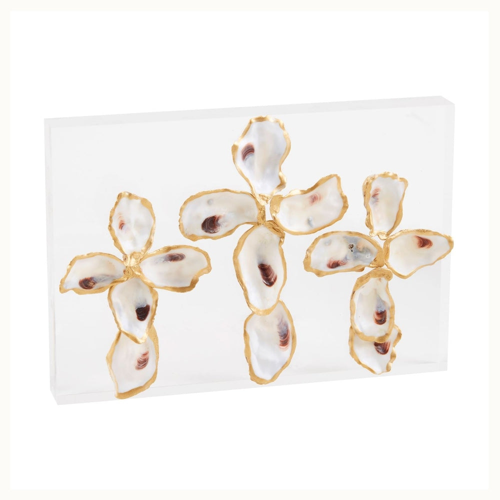 Mixed media sculpture of three oyster shell crosses with gold-leafed edges mounted on a transparent rectangular acrylic block featuring natural iridescent white interiors and deep purple muscle scars