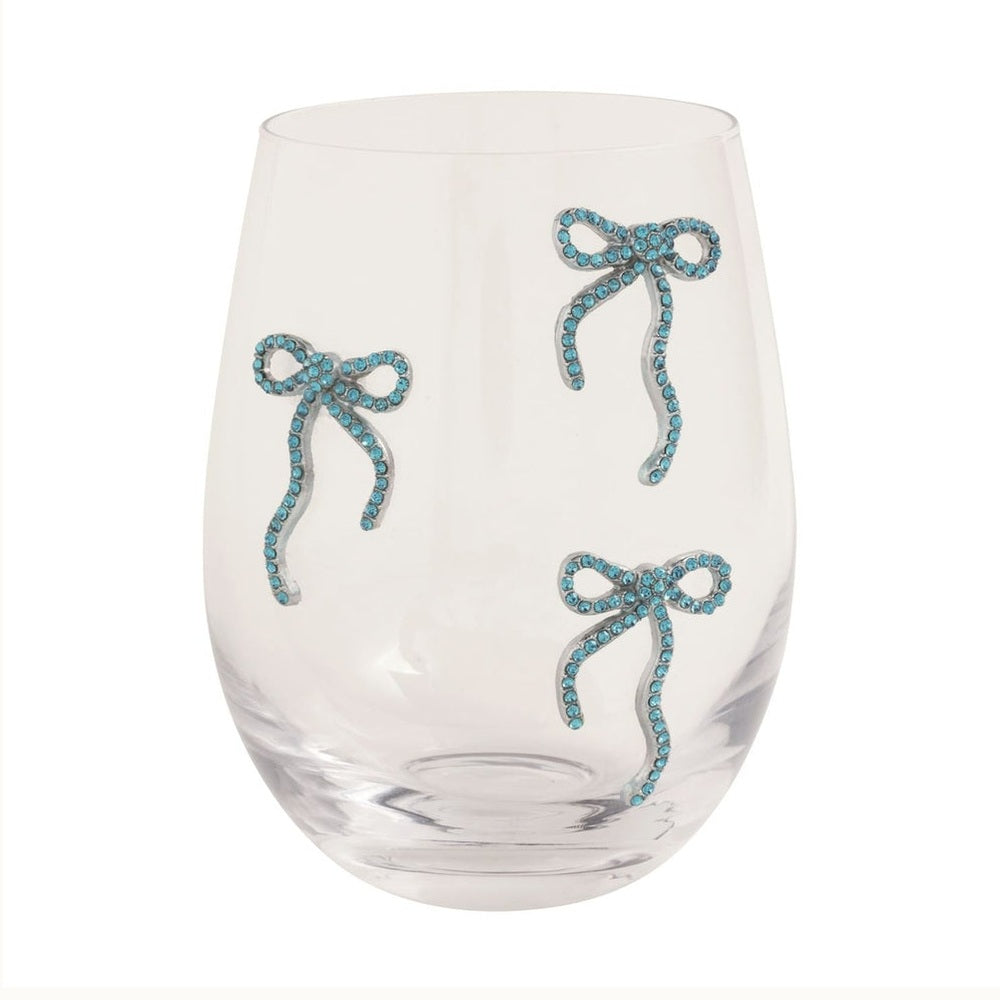 Stemless glass tumbler by Joanna Buchanan featuring three bow motifs embellished with shimmering aquamarine crystals and polished silver-tone metal against a clean white background