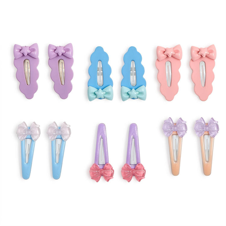 Digital studio photograph of a twelve-piece set of pastel snap hair clips for children on a white background featuring scalloped edges, bow accents with star centers, and glittery translucent finishes in shades of lavender and peach
