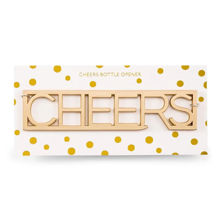 Gold-toned metal bottle opener spelling the word CHEERS mounted on a white card with gold foil polka dots featuring stencil-style serif lettering and a reflective metallic finish