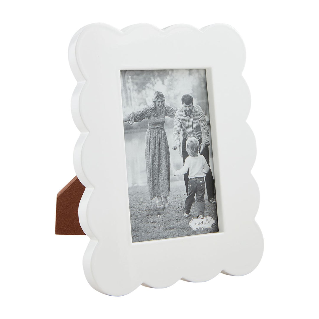 Mud Pie white scalloped picture frame featuring a black and white family portrait in an outdoor grassy field with glossy wavy edges and a contrasting brown easel back