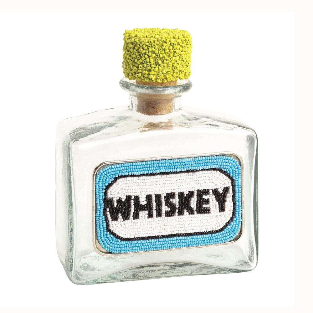 Beaded glass sculpture by Jonathan Adler of a clear whiskey bottle on a white background featuring a textured lime green beaded stopper and a turquoise blue label with bold black lettering