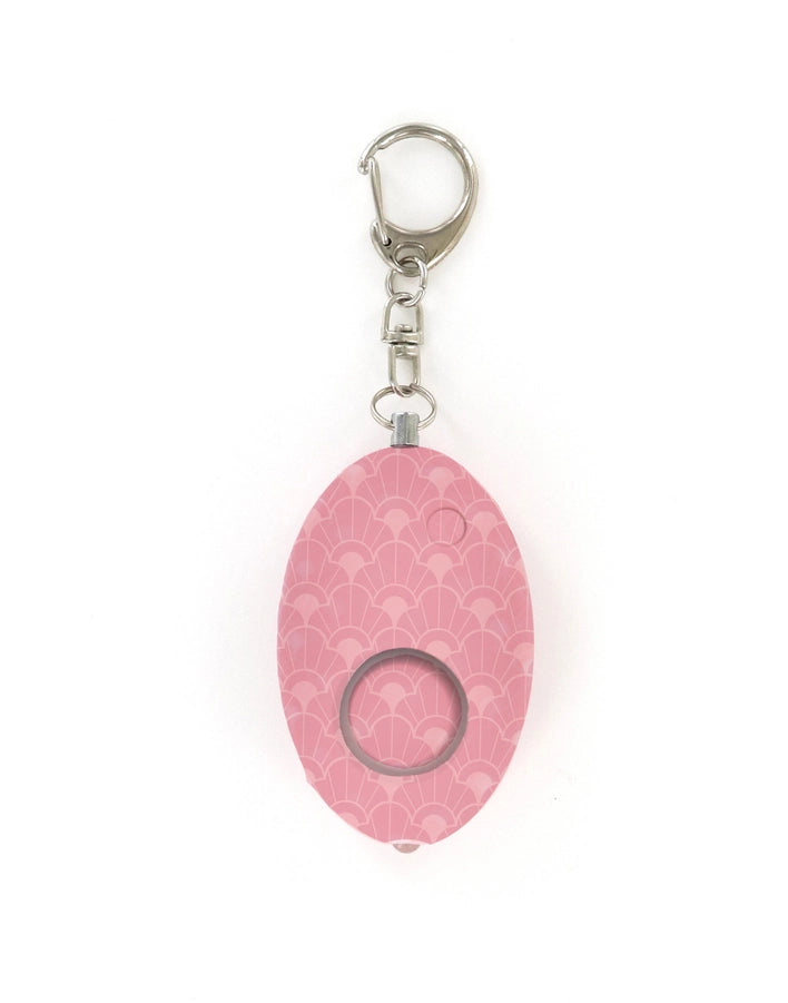 Product photograph of a personal safety alarm keychain on a white background featuring a pink scalloped art deco pattern and a circular silver metal lobster clasp