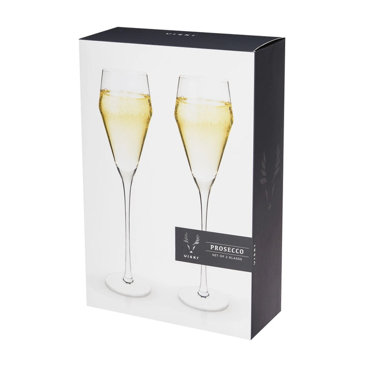 Photograph by Viski of a pair of elegant long-stemmed crystal prosecco glasses filled with effervescent golden liquid displayed in a modern black and white retail box featuring a distinct antler logo
