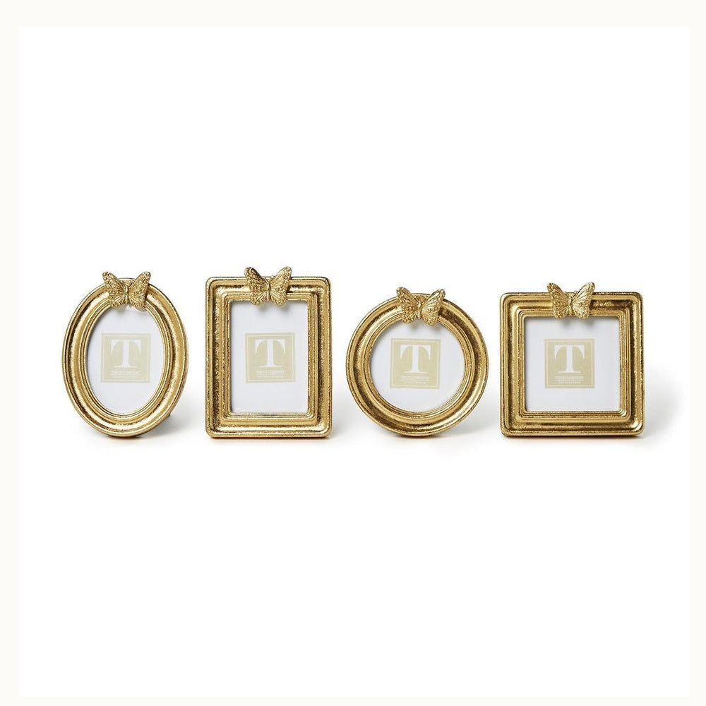 Gold-finished resin frames by Two's Company displayed on a white background, featuring decorative butterfly accents, a textured hammered finish, and four distinct geometric shapes including oval and square silhouettes