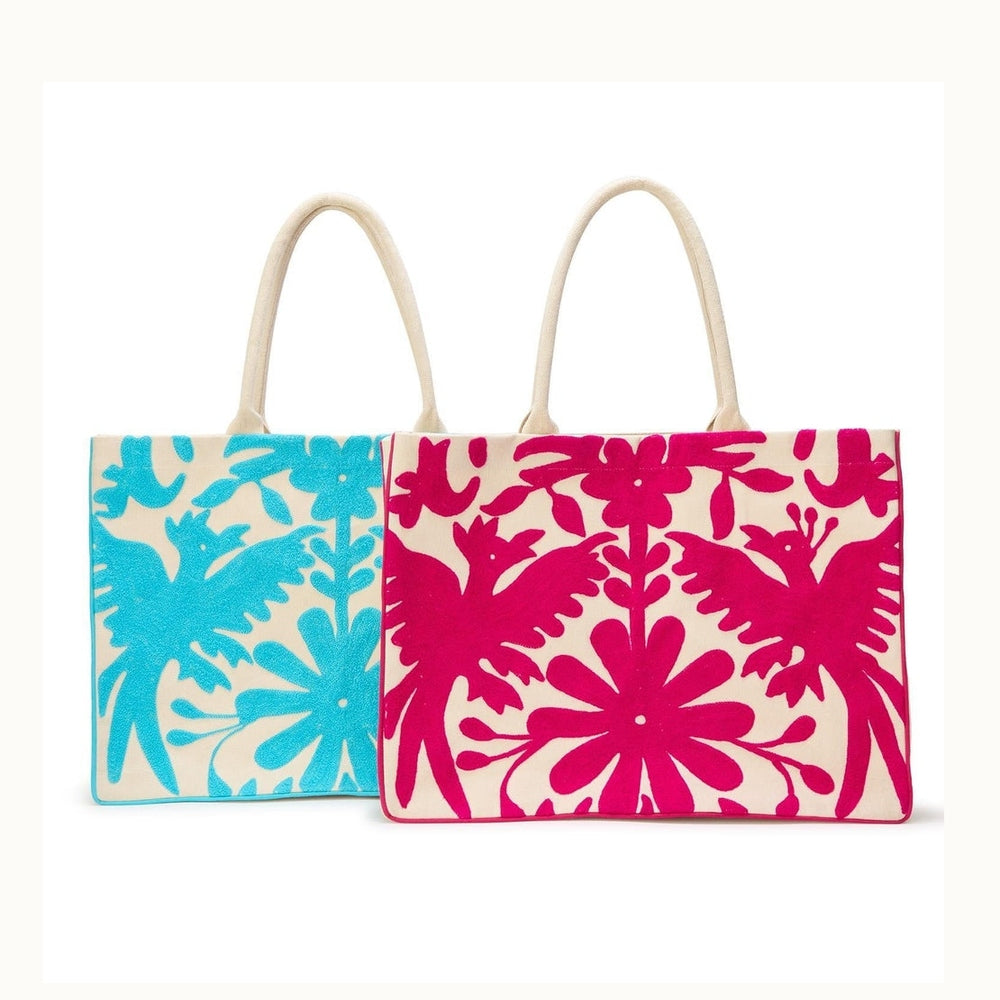 Hand-embroidered Mexican Otomi canvas tote bags featuring traditional Tenango folk art patterns of vibrant turquoise and magenta pink birds and floral motifs with cream rope handles against a white background