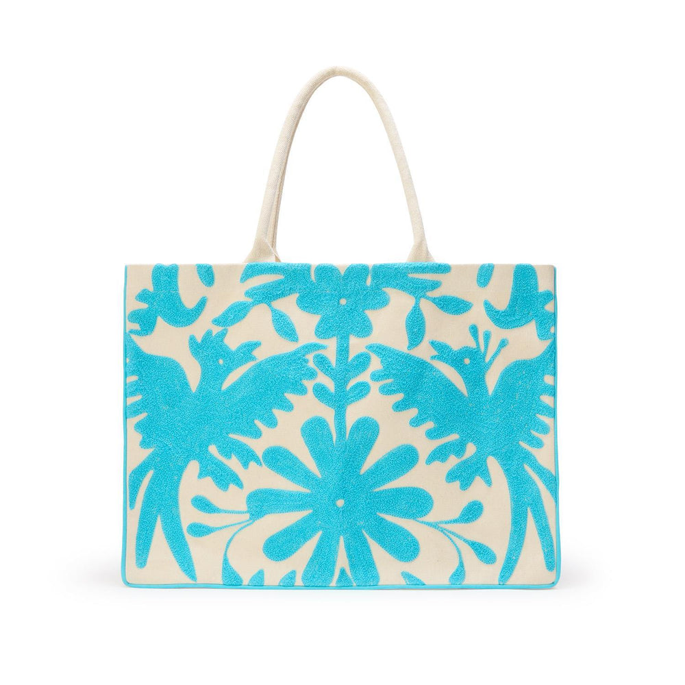 Mexican Tenango embroidered canvas tote bag featuring symmetrical turquoise blue birds and central blooming flowers with textured raised stitching and woven handles on a white background