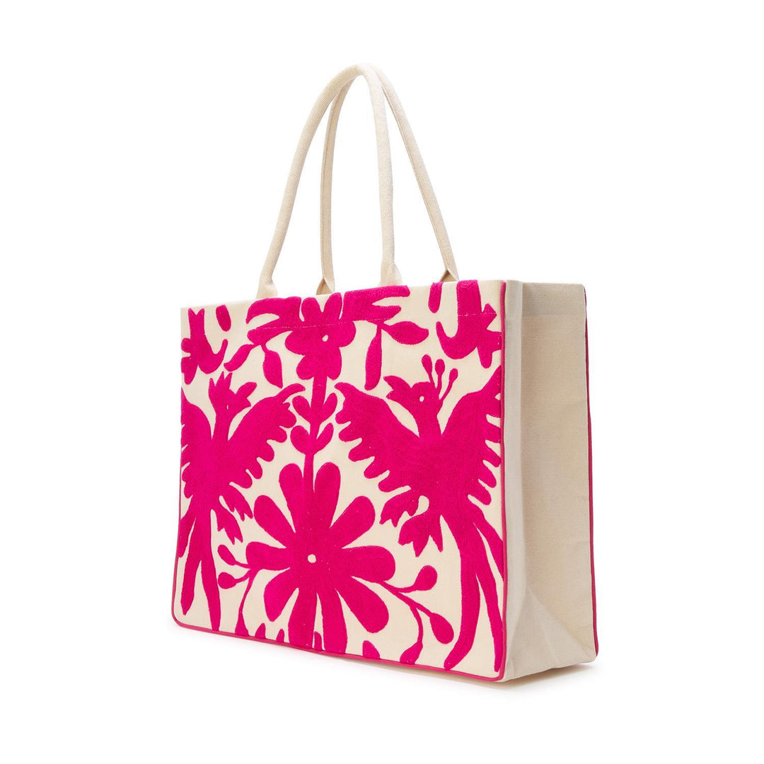 Otomi style hand-embroidered canvas tote bag featuring vibrant hot pink bird motifs and intricate Tenango floral patterns on a cream fabric base against a white studio background