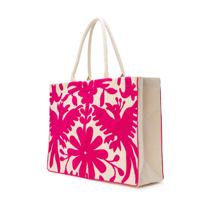 Otomi style hand-embroidered canvas tote bag featuring vibrant hot pink bird motifs and intricate Tenango floral patterns on a cream fabric base against a white studio background