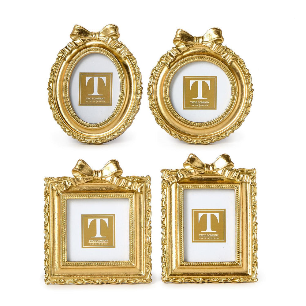 Gold resin picture frames by Two's Company featuring a collection of four ornate oval and rectangular designs on a white background with decorative ribbon bows, beaded inner borders, and intricate filigree carvings
